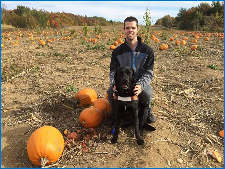 Josué Coudé et son chien-guide dans un champ de citrouilles